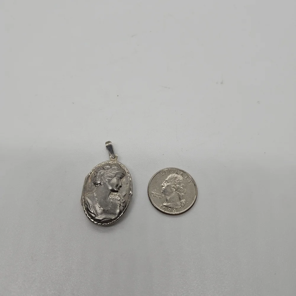 silver tone oval shaped locket style pendant with woman's silhouette
